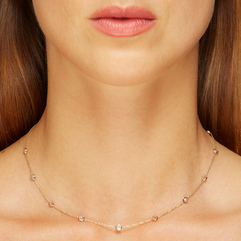 This delicate 14 karat gold necklace is handmade and features sparkling bezel - set stones. Diamond gold necklace.
